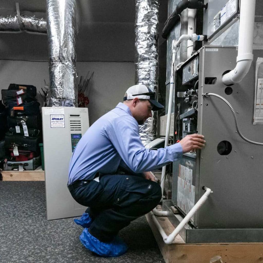 An Atchley Air worker inspecting the internals of an air conditioning unit