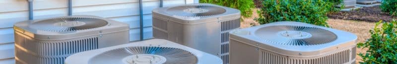 A group of 3 air conditioning units outside all clean and properly maintained